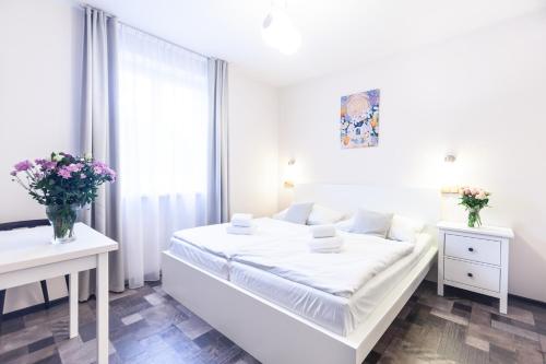 a white bedroom with a white bed and a window at Apartmány U zámku in Český Krumlov