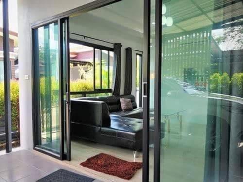 a living room with a black couch and glass doors at Comfy house near sunset beach in Koh Samui