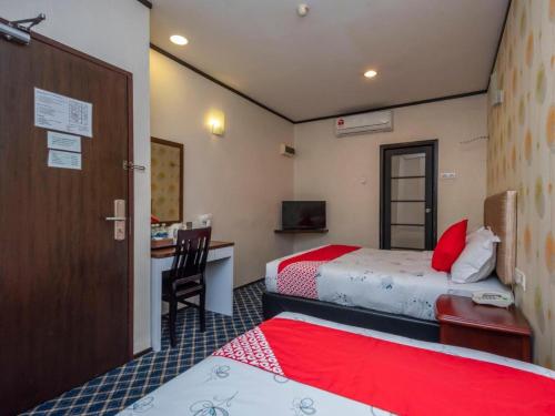 a hotel room with two beds and a desk at Suan Bee Hotel@Sutera in Skudai