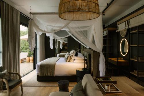 a bedroom with a canopy bed and a window at Zambezi Sands by Batoka in Victoria Falls