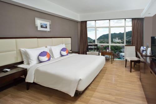 um quarto com uma grande cama branca e uma grande janela em FOX Hotel Gorontalo em Gorontalo