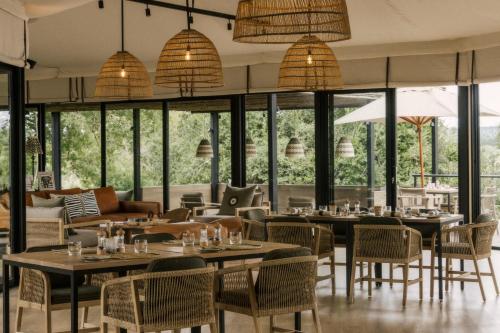 a restaurant with tables and chairs and windows at Zambezi Sands by Batoka in Victoria Falls