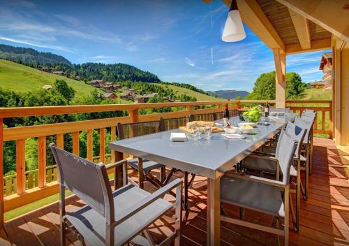 une terrasse en bois avec une table et des chaises dessus dans l'établissement Chalet Meringue - Les Congères, au Grand-Bornand
