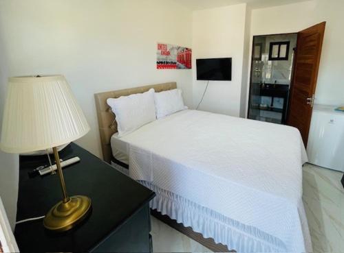 a bedroom with a bed and a lamp on a table at Residence Pipa Beach in Pipa