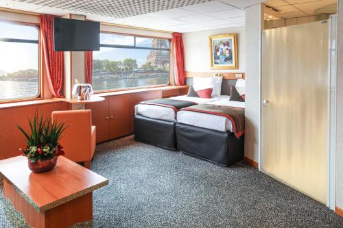 a room with a bed and a table and a window at Bateau Seine Princess by CroisiEurope in Paris