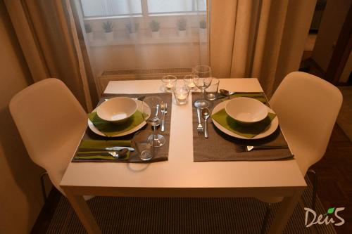 a white table with chairs and plates and glasses on it at Ferienwohnung DEU5 in Bregenz