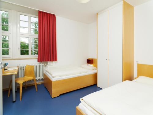 a room with two beds and a desk and a table at Bildungshaus Neckarelz in Mosbach