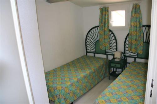 une petite chambre avec deux lits et une fenêtre dans l'établissement Les Toscanes, appartement 6 pers, plage richelieu, au Cap d'Agde