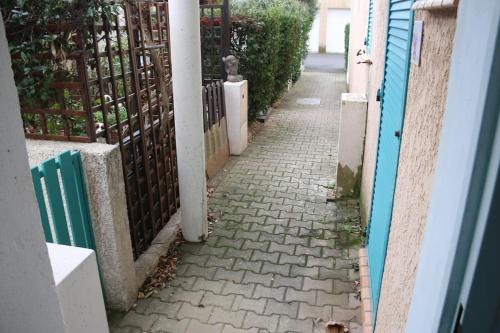 une ruelle avec une clôture et un trottoir en briques dans l'établissement Les Toscanes, appartement 6 pers, plage richelieu, au Cap d'Agde