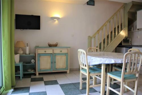 un salon avec une table et des chaises et un escalier dans l'établissement Les Toscanes, appartement 6 pers, plage richelieu, au Cap d'Agde