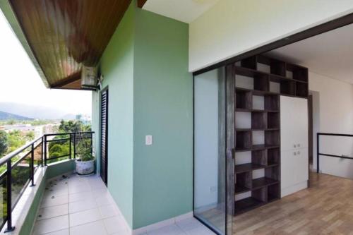 a room with a green wall and a balcony at Apartamento cobertura duplex Ubatuba - Praias Tenório e Grande in Ubatuba