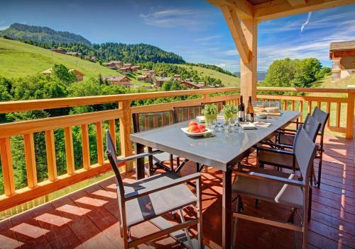 une terrasse en bois avec une table et des chaises dessus dans l'établissement Chalet Macaron - Les Congères, au Grand-Bornand