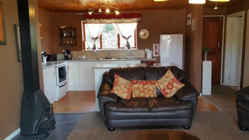 a living room with a leather couch and a kitchen at Berghaven in Underberg