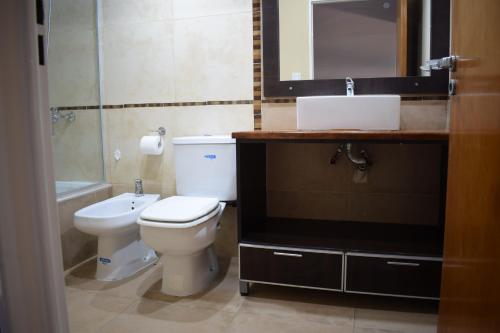 uma casa de banho com um WC, um lavatório e um espelho. em Duplex Jacaranda II em Ciudad Evita