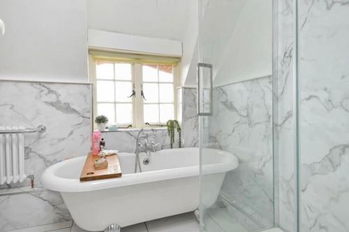 a white bathroom with a tub and a shower at Sea Breeze in South Hayling