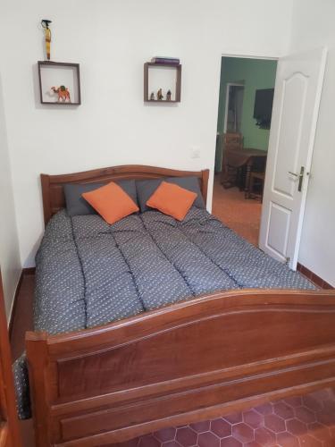 - une chambre avec un lit en bois et des oreillers orange dans l'établissement T3 Provençal à la Ciotat, à La Ciotat