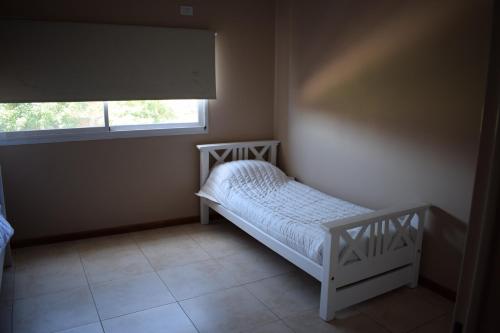 um pequeno quarto com uma cama e uma janela em Duplex Jacaranda II em Ciudad Evita