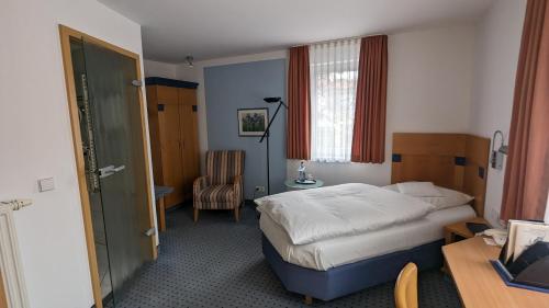 a hotel room with a bed and a chair at Hotel Gasthof Lang in Balingen
