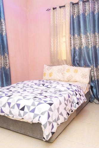uma cama num quarto com cortinas azuis em Legacy Apartment Phase 1 em Brufut