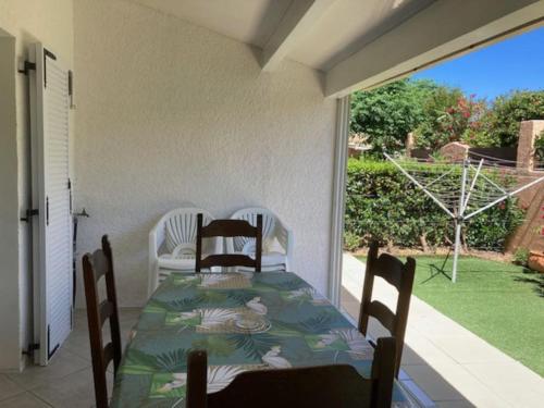 une véranda avec une table, des chaises et une fenêtre dans l'établissement Hacienda Beach 2 Villa pour 6 personnes, au Cap d'Agde