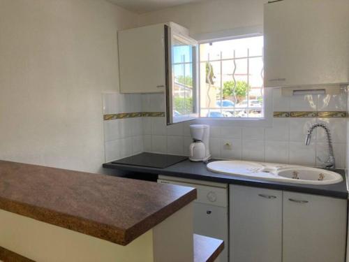 une cuisine blanche avec un évier et une fenêtre dans l'établissement Hacienda Beach 2 Villa pour 6 personnes, au Cap d'Agde