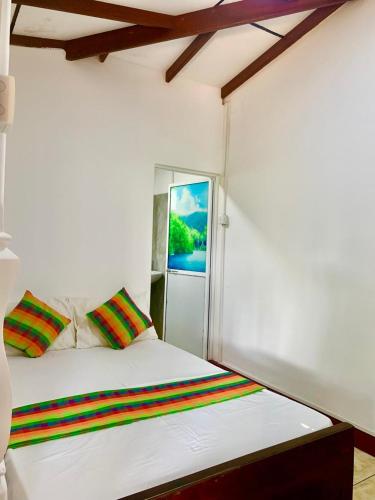 a white bed with colorful pillows in a room at Surf Front in Ahangama