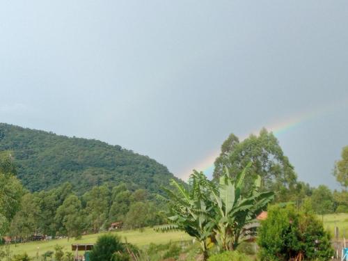 un arco iris en el cielo sobre un campo con árboles en Chácara mãos de Gaia en Bragança Paulista