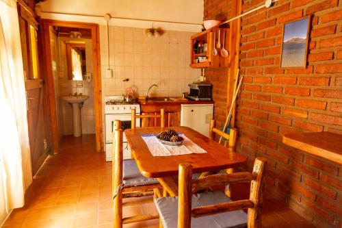 a kitchen with a wooden table and a brick wall at Costa del Río in Lago Puelo