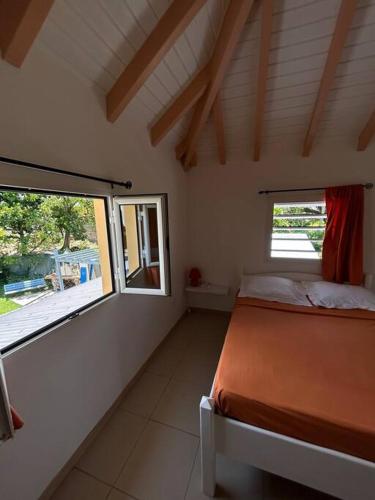 a bedroom with a bed and two windows in it at Logement Ghenoah in Petit-Canal