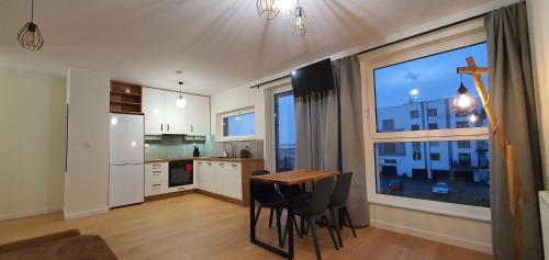 a kitchen with a table and chairs and a large window at Oak Apartament Rumia Aquapark in Rumia