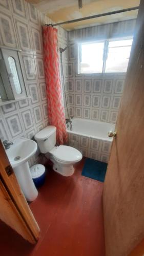baño con 2 aseos, lavamanos y ventana en Cabañas Altos del Poeta, en Isla Negra