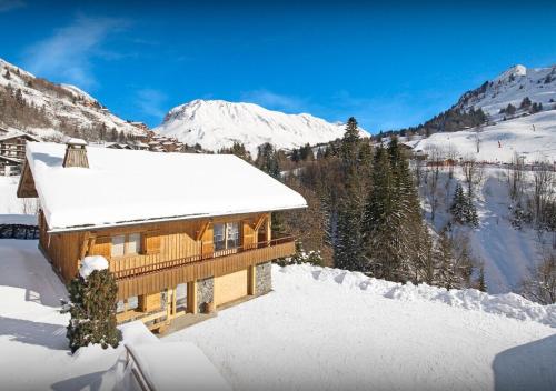 a log cabin in the snow with mountains in the background at Chalet Joubarbe - Les Congères in Le Grand-Bornand