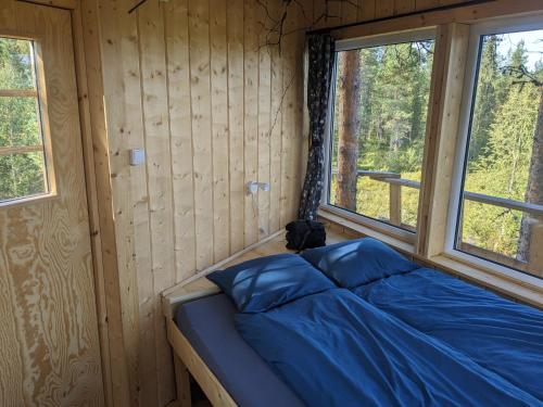 a bed in a wooden room with two windows at Aurora Lodge in Jerfojaur