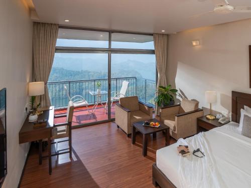 a hotel room with a bed and a desk and a balcony at Ragamaya Resort & Spa Munnar in Munnar