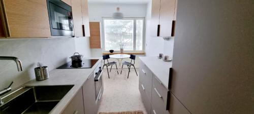 una cocina con encimeras blancas, mesa y sillas en Apartment in Tapiola, en Espoo
