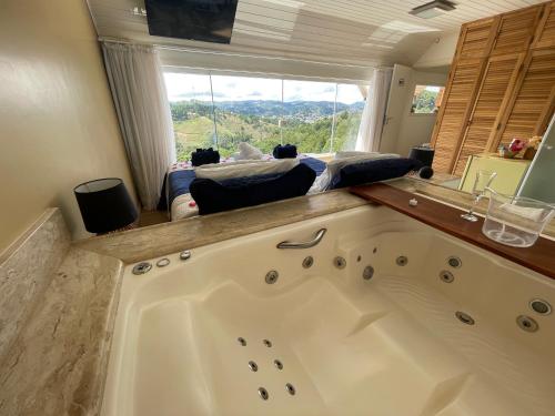 a large bathroom with a large tub in front of a window at Bela Vista Chalé in Campos do Jordão