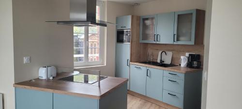 une cuisine avec des armoires bleues et un comptoir dans l'établissement Les résidences de la capitainerie, au Tréport