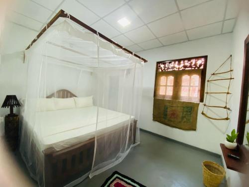 um quarto com uma cama de dossel e uma janela em Art house hiriketiya em Dickwella
