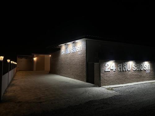 a brick building with neon signs on it at night at 24 Sleep Resort Khlong Luang Hospital in Khlong Luang