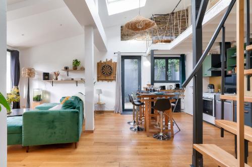 un salon avec un canapé vert et une cuisine dans l'établissement Charmante maison plain-pied et son jardin fleuri, à Nantes