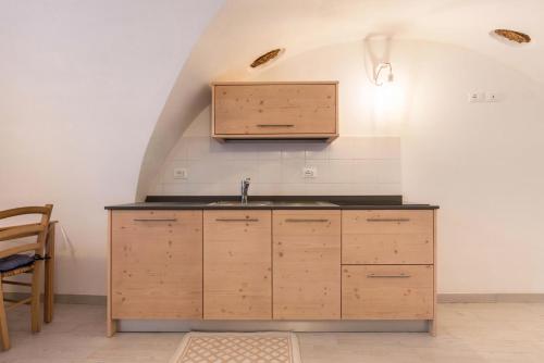 Una cocina con gabinetes de madera y un fregadero. en Logge dei Paroloti, en Dorsino