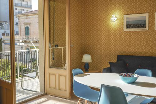 Habitación con mesa, sillas y balcón. en Casa della Villa Pozzallo en Pozzallo