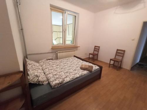 a bedroom with a bed with two chairs and a window at Rooms in the Centrum in Warsaw