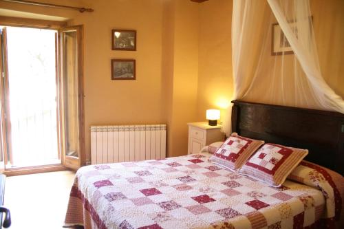 a bedroom with a bed with a quilt and a window at Cal Pallerola in Montargull de la Vansa