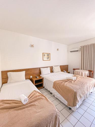 a hotel room with two beds and a chair at Sunshine Praia Hotel in Porto Seguro