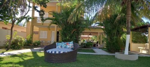 einen Korbstuhl vor einem Gebäude mit Palmen in der Unterkunft O melhor lugar pra família, em Tamandaré in Tamandaré