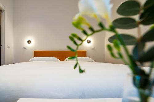 a bedroom with a white bed with a vase with a plant at Terra Mia in Piazza in Pompei
