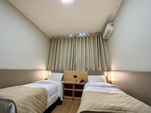 2 camas en una habitación pequeña con ventana en Hotel Alji, en Indaiatuba