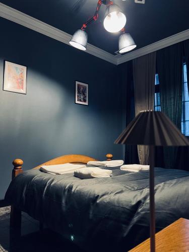 a bedroom with a bed with blue walls and a lamp at Central Apartment Black Cat in Karlovo