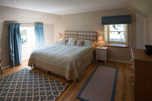 ein Schlafzimmer mit einem Bett und einem blauen Teppich in der Unterkunft Keeper's Cottage, Straloch Estate in Perth